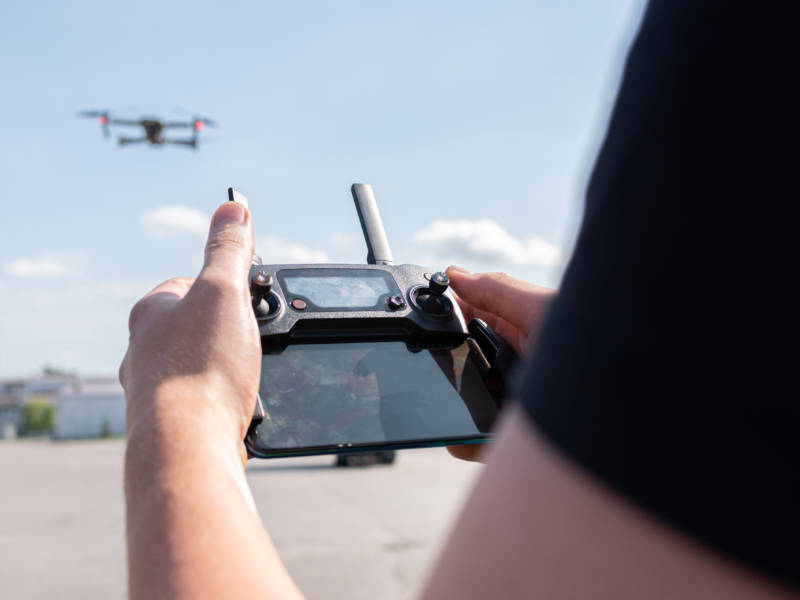Dronelupakorttia suorittava opiskelija ohjaa dronea kauko-ohjaimella.