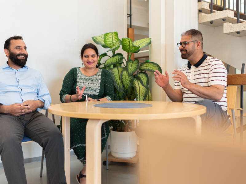 Kolme Edusalon kansainvälistä opiskelijaa juttelevat pöydän äärellä.
